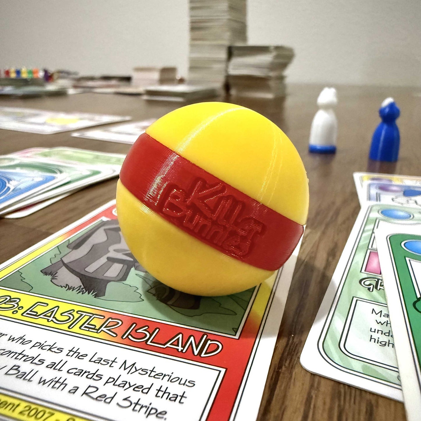 Quest 3D Yellow Ball with a Red Stripe on a table with cards