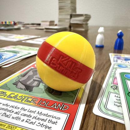 Quest 3D Yellow Ball with a Red Stripe on a table with cards