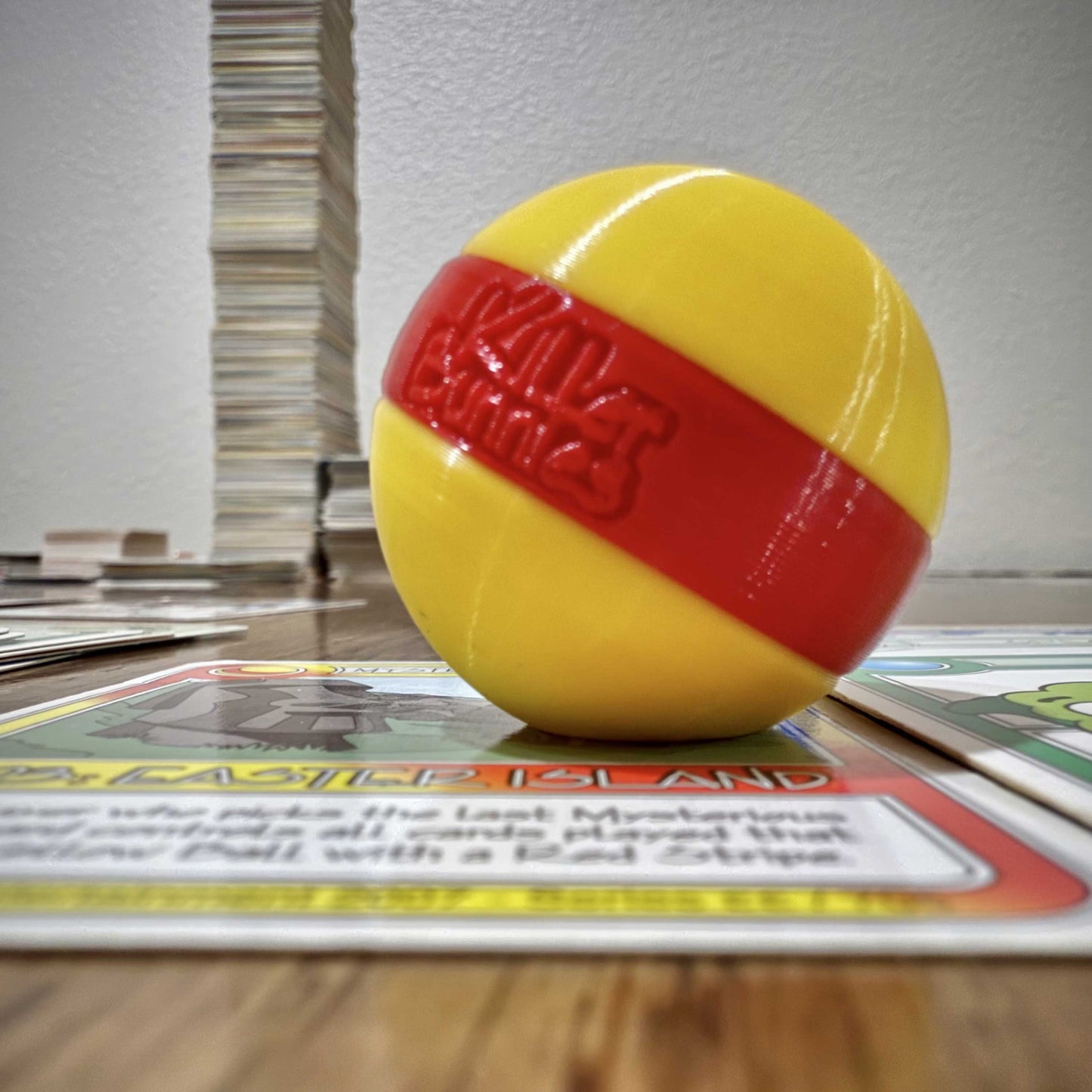 Quest 3D Yellow Ball with a Red Stripe on a table with cards