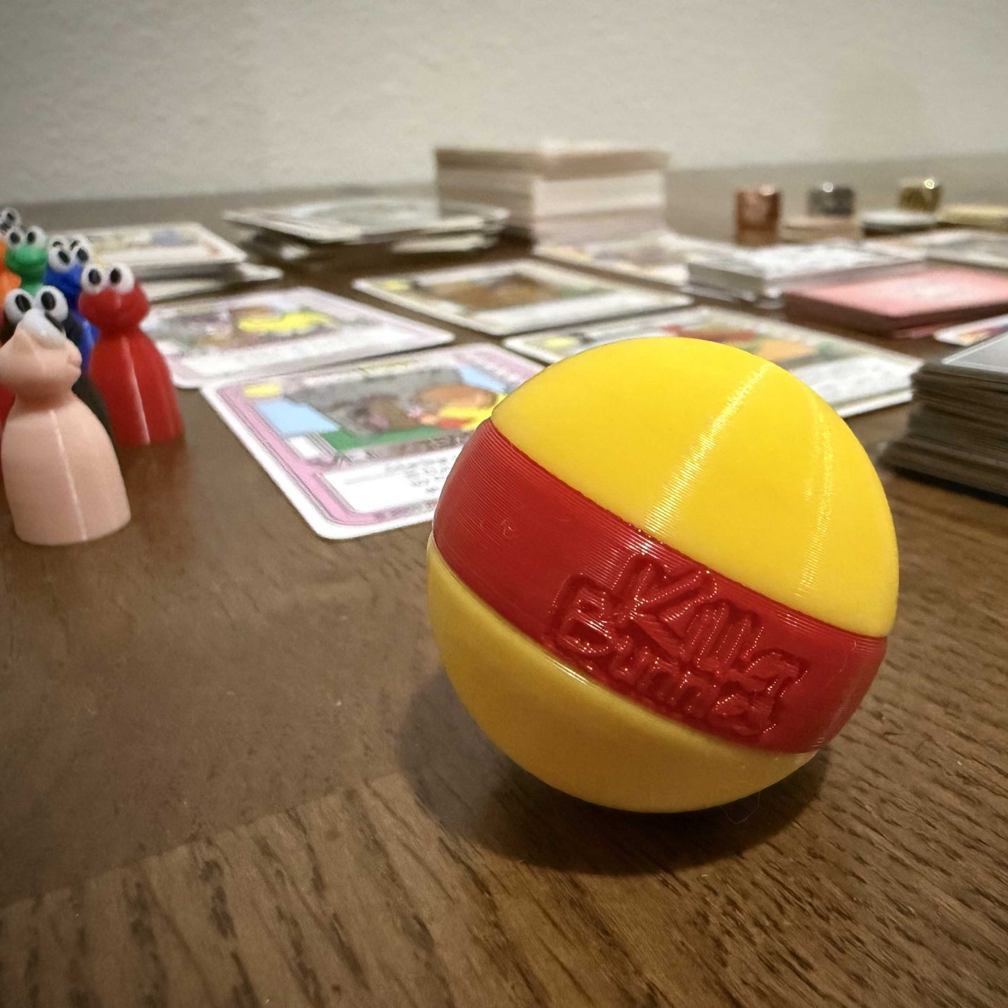 Quest 3D Yellow Ball with a Red Stripe on a table with cards